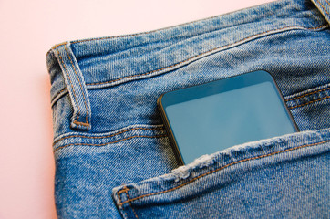 Smartphone with a gray screen in close-up in a jeans pocket. Smartphone in a pocket on a pink, white, blue  background