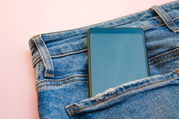 Smartphone with a gray screen in close-up in a jeans pocket. Smartphone in a pocket on a pink, white, blue  background