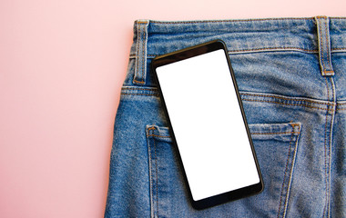 White screen smartphone in jeans pocket. Smartphone place for text. Smartphone in a pocket on a pink background.  Copy Space