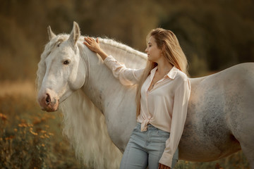 Beautiful young woman with white tinker cob in an autumn field