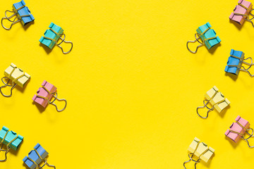 Colorful binder clips on bright yellow background with copy space for your design. Back to school...