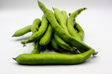 pile of fresh green broad beans in their shells isolated on a white background