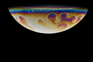 Imitation of an unknown planet. Soap bubble. Close-up. Black background. Bright colors. Fantasy.