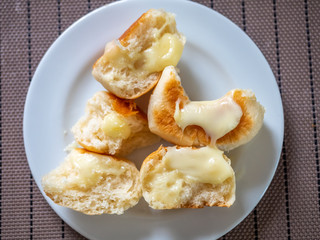 Homemade buns topping with melting milk cheese on white plate, top view