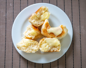 Homemade buns topping with melting milk cheese on white plate, top view