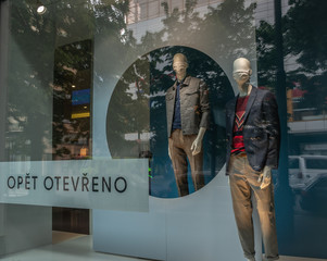 Two mannequin men wearing surgical face masks in shopping window display during Covid19/Corona virus pandemic in Prague