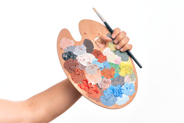 Hand of caucasian young man holding paintbrush and palette with colors over isolated white...