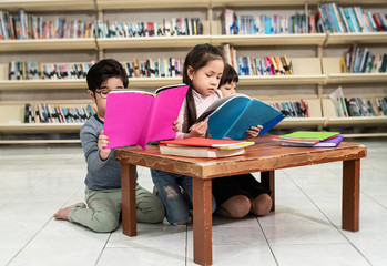 Three children reading book together at school,with interested feeling,blurry light around