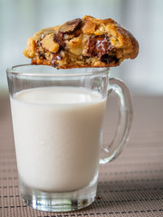 Crunchy chewy chocolate chip soft cookie on cup of milk, selective focus at melting chocolate