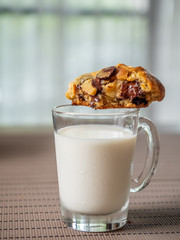 Crunchy chewy chocolate chip soft cookie on cup of milk, selective focus at melting chocolate