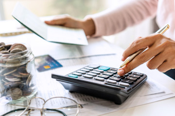 Young Asian woman checking bills, taxes, bank account balance and calculating credit card expenses. Family expenses concept.