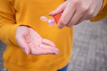A young girl in a yellow sweater disinfects the hands with an antiseptic