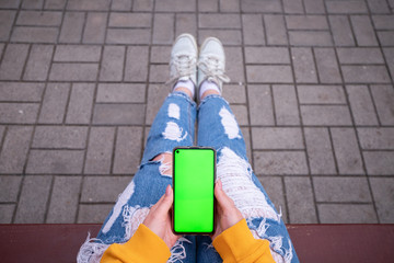 Young girl in a yellow sweater holds a phone with a green screen