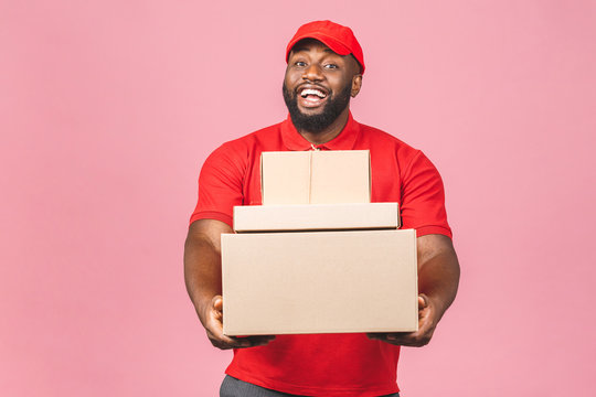 Delivery concept. African american delivery black man carrying parcel isolated over pink background.