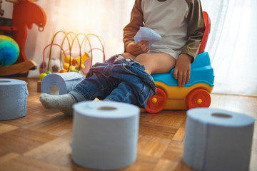 Cute toddler boy, potty training. Infant child baby boy toddler sitting on potty, playing with toys...