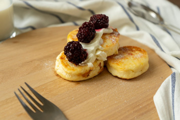 Cheesecakes with sour cream and blackberry berries on a wooden tray