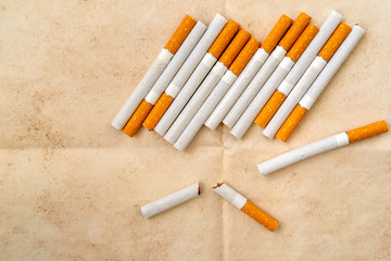 Broken cigarettes on old paper background