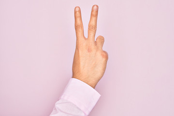 Hand of caucasian young man showing fingers over isolated pink background counting number 2 showing...