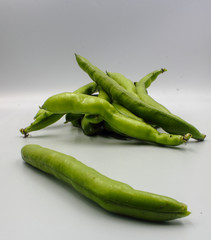 pile of fresh green broad beans in their shells isolated on a white background
