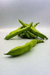 pile of fresh green broad beans in their shells isolated on a white background