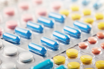 pile of medical pills  in red, blue and yellow colors in  silver plastic packaging