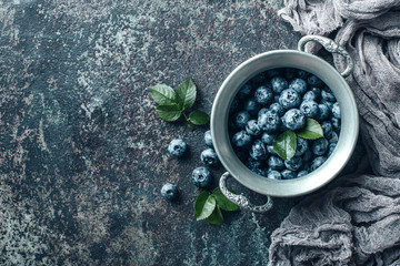 Fototapeta na wymiar Freshly picked blueberries in bowl on old metal background. Healthy eating and nutrition.