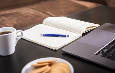 Home workspace, office online. Table with notebook, laptop, cup of coffee and  biscuit