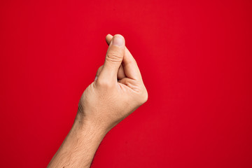Hand of caucasian young man showing fingers over isolated red background holding blank space with...