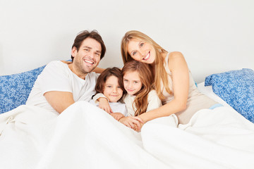 Fototapeta premium Happy parents with children together in bed