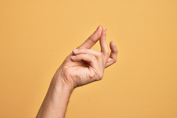 Hand of caucasian young man showing fingers over isolated yellow background snapping fingers for...