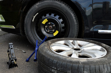 Tire change with spare tire and aluminum rim following a puncture, with a lug wrench and jack