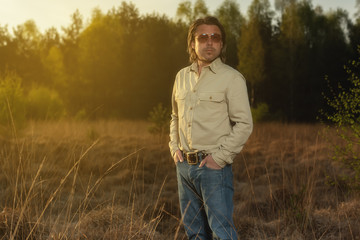 Man in shirt and sunglasses in nature at sunrise during spring.