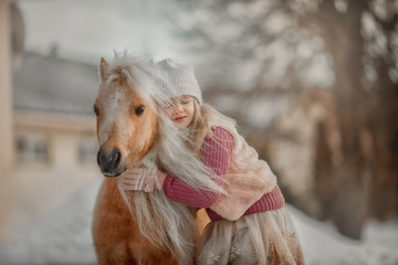 Little girl with palomino miniature horse stallion in winter park
