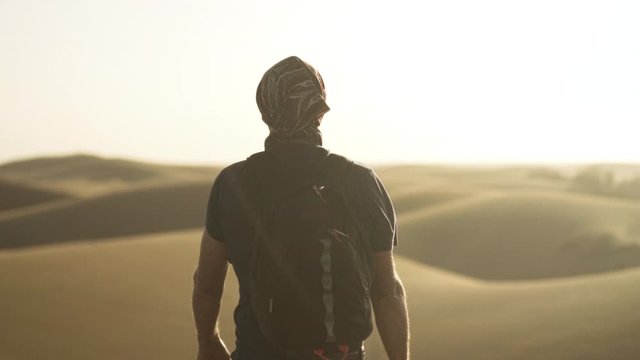 Man Walking Through Sunlit Desert
