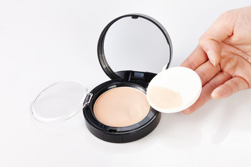 Hand that use foundation compact and puff.