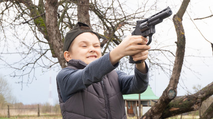 a boy in a black cap shooting a pistol at targets. weapon. sport shooting.