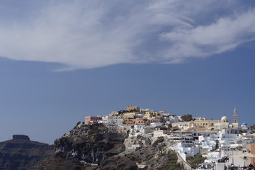 Fototapeta na wymiar Fira, Santorini, Greece: Houses, churches, shops, and cafes shine in the sun on a hillside in the city of Fira on the Aegean island of Santorini.