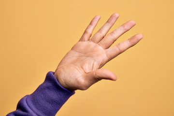 Hand of caucasian young man showing fingers over isolated yellow background presenting with open palm, reaching for support and help, assistance gesture