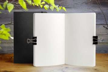 Notebook mockup on wooden table with gray wall background, Green birch leaves in frame, mock up