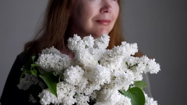 Woman holds bouquet of white lilacs