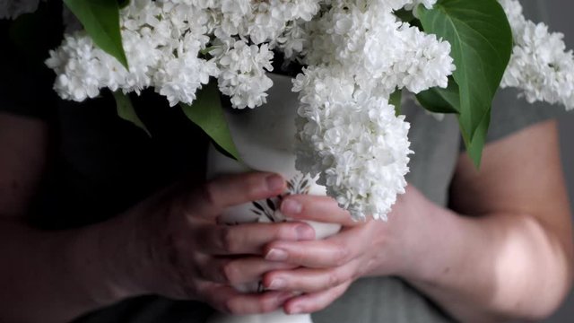 woman hands holding vase of white flowers