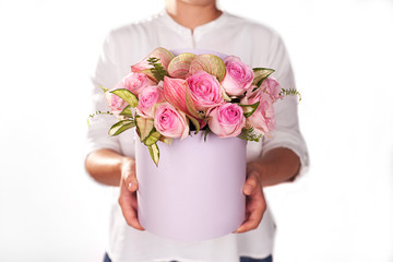 a bouquet of flowers in a round  box on a white background. Florist girl showing off a bunch 