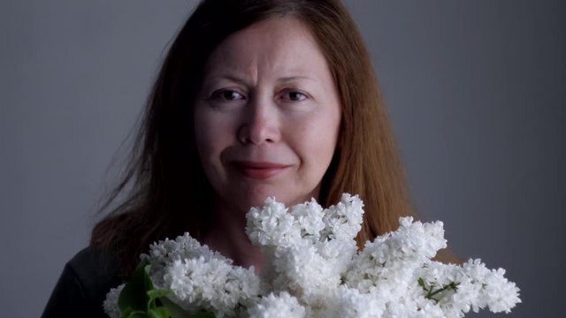 Portrait of young woman with white flowers of lilacs