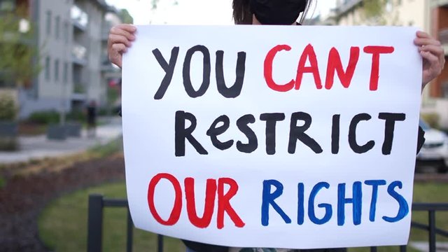 Activist girl with a poster you cant restrict our rights in hands. Woman wears black protective mask, protest during quarantine of coronovirus covid-19
