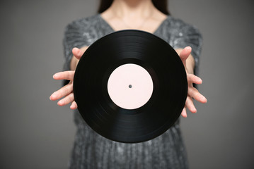 A singer with blank vinyl record in hands close up on gray background.