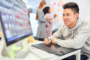 Graphic designer with pen and tablet designs layout