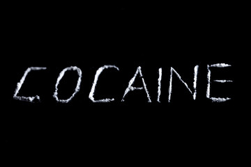 the word cocaine from white powder on a black background