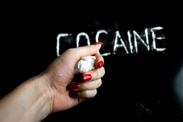 hand squeezes cellophane bag with white powder (drug), the word 