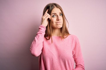 Young beautiful redhead woman wearing casual sweater over isolated pink background worried and stressed about a problem with hand on forehead, nervous and anxious for crisis