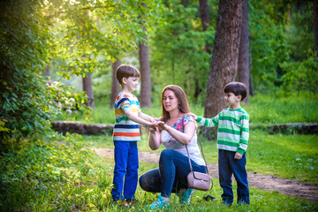 Young woman mother applying insect repellent to her two son before forest hike beautiful summer day or evening. Protecting children from biting insects at summer. Active leisure with kids